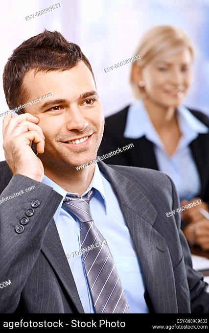 Businessman talking on mobilephone smiling looking aside in office