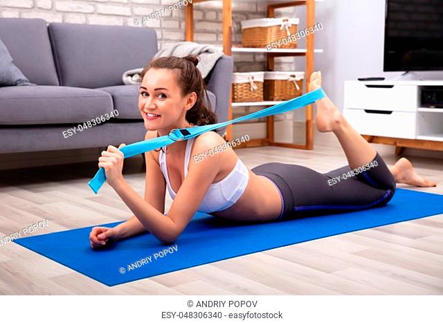 Happy Young Woman In Sportswear Doing Workout With Yoga Belt At Home