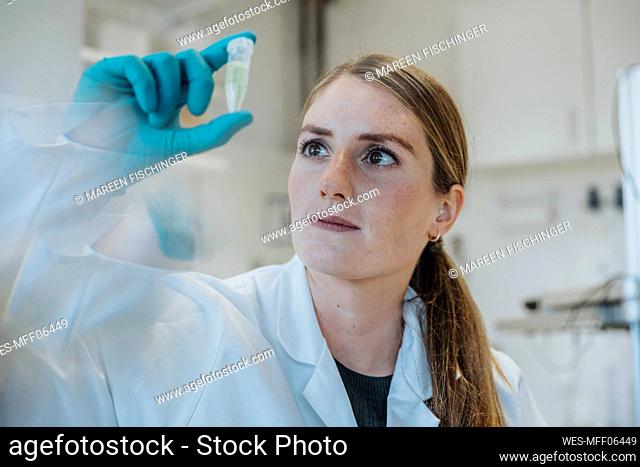 Young woman examining test tube while standing at laboratory