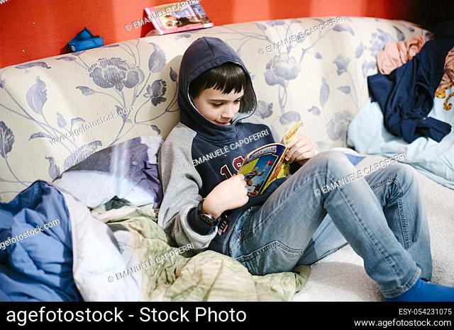 Child reads comics on the couch