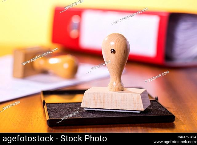 Schreibtisch mit Stempel, Aktenordner und einem Dokument