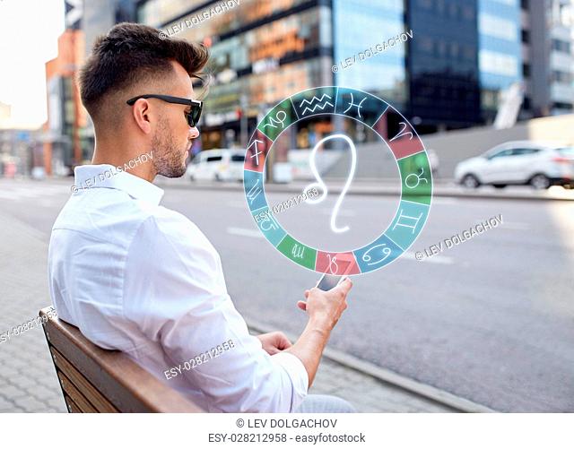 technology, astrology, horoscope and people concept - close up of man with smartphone and leo zodiac sign in city