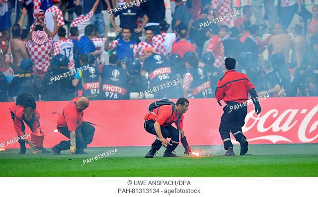 Service personnel collect flares on the pitch during the Euro 2016 Group D soccer match between Czech Republic and Croatia at the Stade Geoffroy-Guichard in...