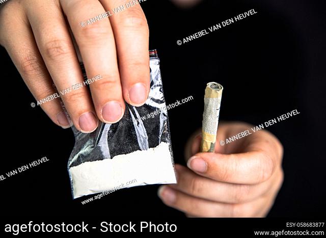Drug dealer Giving drugs in a plastic bag, cocaine, heroin, speed or other drugs on dark black background, addiction, drugs, junky, criminal concept copy space