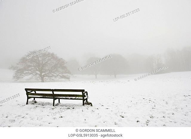 England, Essex, Westley Heights. An empty bench overlooking a snow covered field