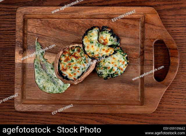 Delicious stuffed mushrooms with spinach and cheese isolated on wooden background