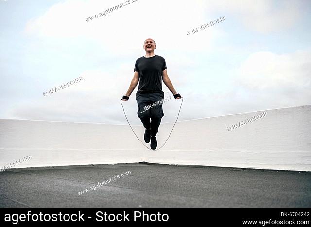 A man exercising on the rooftop using a jumping rope during lockdown, Portugal, Europe
