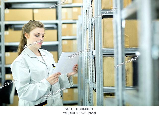 Young woman in storehouse looking at paper