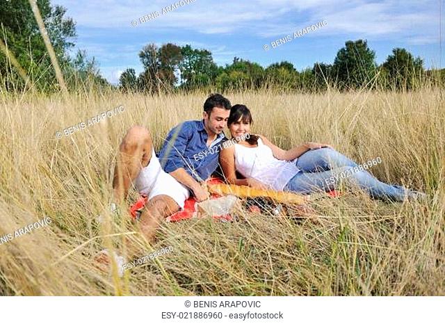happy couple enjoying countryside picnic in long grass