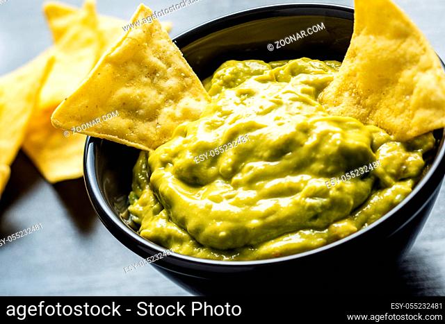 Corn nacho chips and avocado dip. Yellow tortilla chips and guacamole in bowl