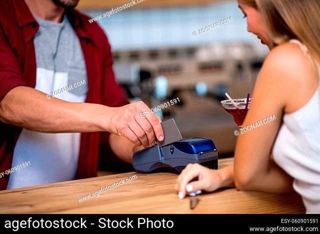 Handsome Man Scans Credit Card In Cafe. Girl Is Waiting At Stand Up Bar. Paying For Coffee
