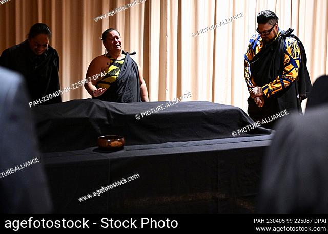 05 April 2023, Baden-Württemberg, Stuttgart: Kalehua Caceres (l) and Mana Caceres (r) from Hawaii stand by the covered remains during a ceremonial return of...