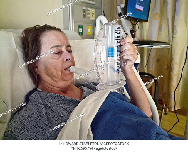 Hospital patient uses a spirometer for breathing therapy following surgery