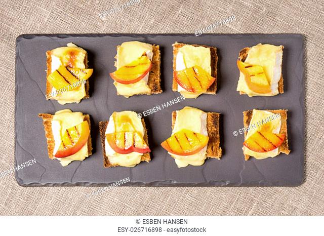 canapes, appitizer with grilled brie and nectarine plated on a slate dish