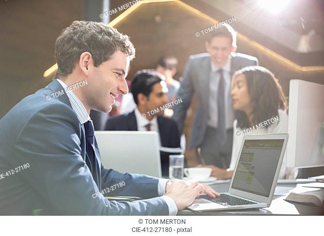 Smiling businessman working at laptop in office