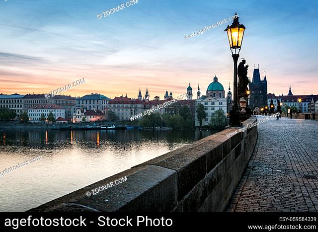 Charles Bridge at sunrise, Prague, Czech Republic. Dramatic statues and medieval towers. Unique view at dawn when there are almost no people on the bridge
