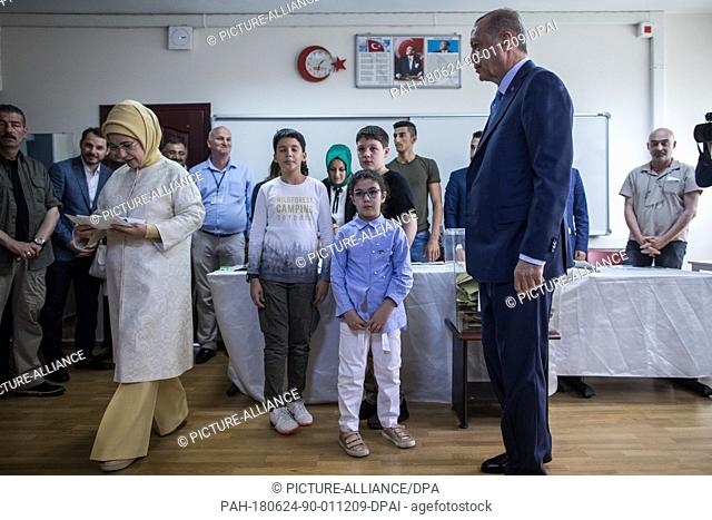 Turkish President Tayyip Recep Erdogan (R) looks on as his wife Emine Erdogan enters a voting booth to cast her ballot in Turkey's elections at a polling...