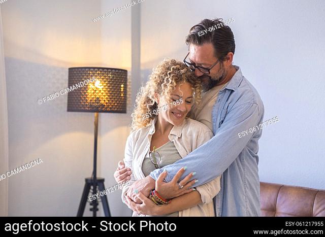 Close up of young adult couple hugging with love at home - life mature people male and female together in relationship embrace with affection - concept of new...