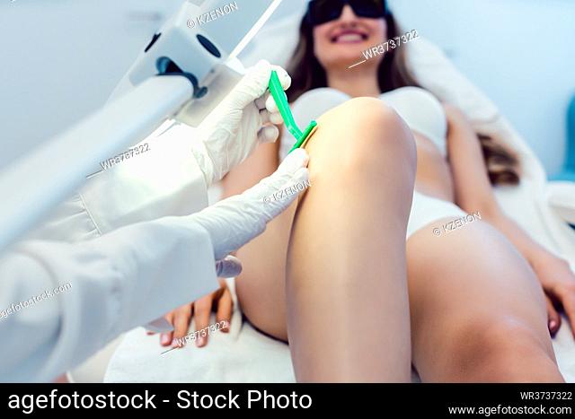 Therapist shaving leg of woman customer before starting hair removal in her beauty parlor