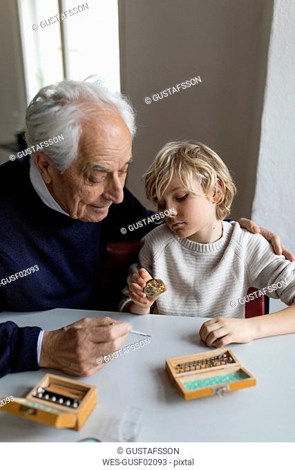 Watchmaker and his grandson examining watch together