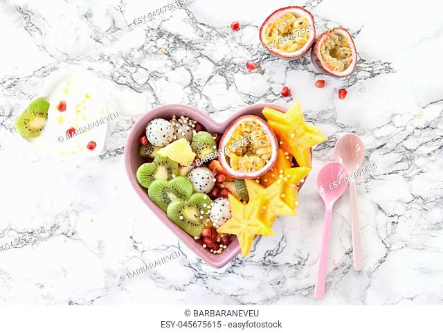 Fresh fruit salad made from exotic fruits in a heart bowl