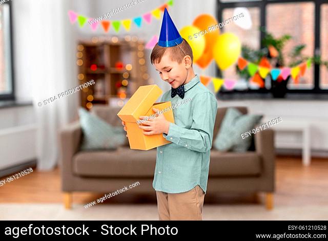 smiling boy in party hat with birthday gift