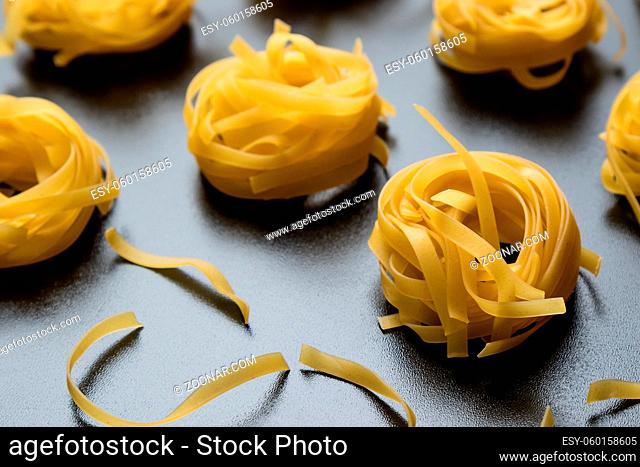 raw dry tagliatelle pasta on black table