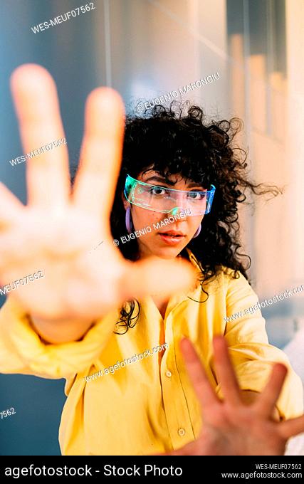 Young woman with cyber glasses doing stop gesture
