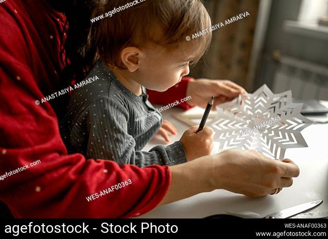 Mother and son making paper snowflakes at home