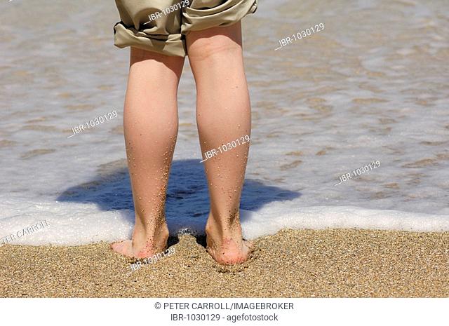 Legs of a girl standing with pants rolled up at Simpson Beach, Oregon, USA
