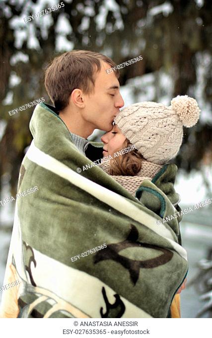 Happy man kissing his beautiful girl on the forehead and covers her blanket. A handsome man kiss on the forehead her beloved, beautiful