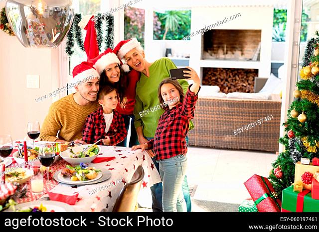 Caucasian multi generation family wearing santa hats taking selfie at christmas time