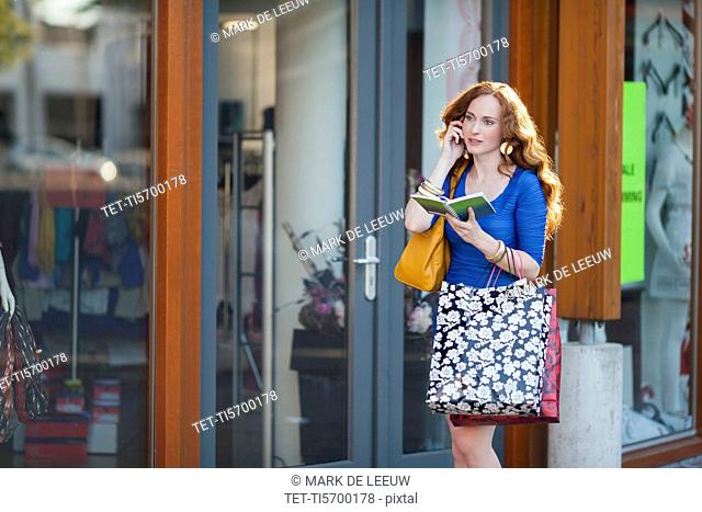 Elegant woman walking street and talking on mobile phone