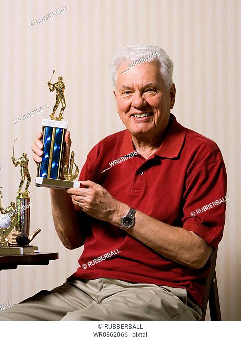 Portrait of a senior man holding a trophy