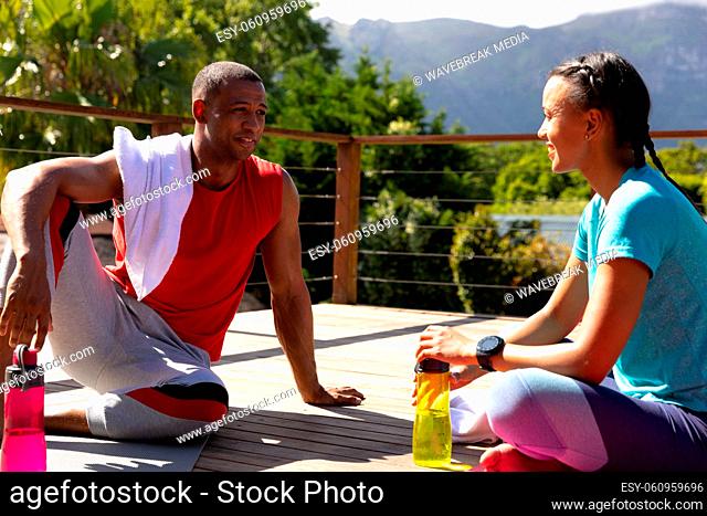 Young african american couple talking while relaxing after yoga session on sunny day