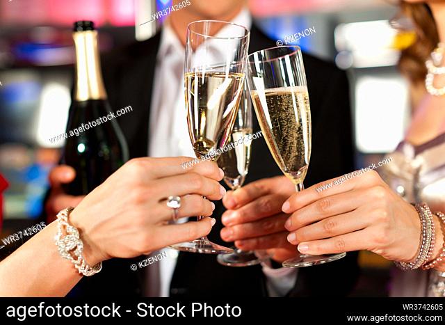 Three friends with champagne in a bar or casino - only torsos to be seen