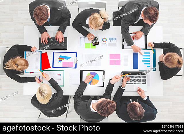 Business people work with statistics data documents with tables and diagrams sitting around the table