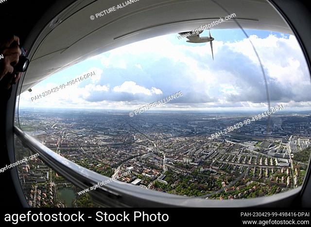 29 April 2023, Bavaria, Munich: White-blue cloudy sky is seen through a window of a zeppelin over the state capital Munich