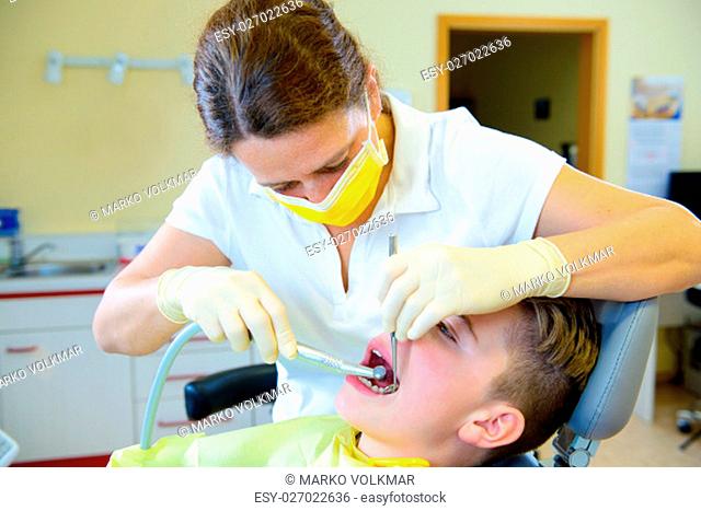 teenager is treated by female dentist in dental surgery