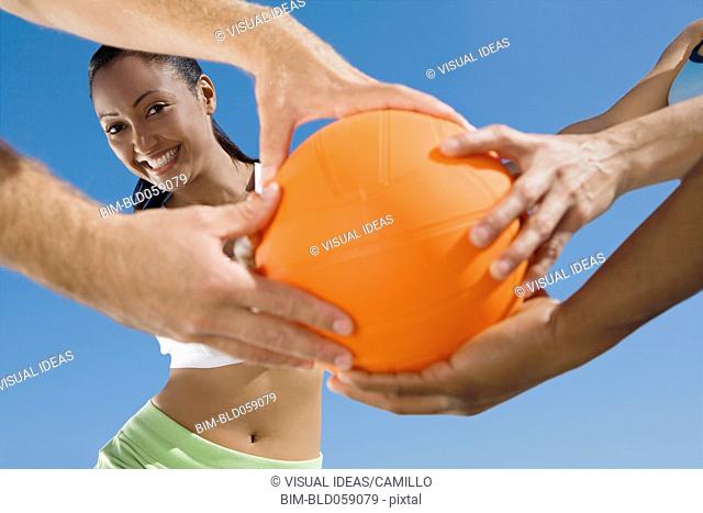 Multi-ethnic friends grabbing volleyball
