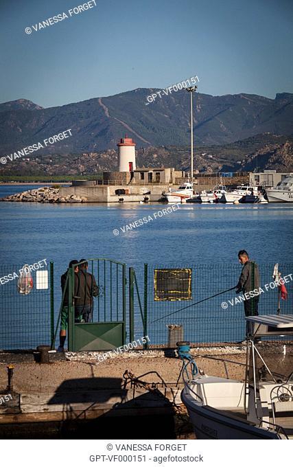 FISHERMEN IN FRONT OF THE PORT AND LIGHTHOUSE OF ARBATAX, SARDINIA, ITALY