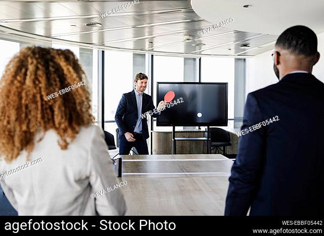 Businessman playing table tennis with colleagues in office