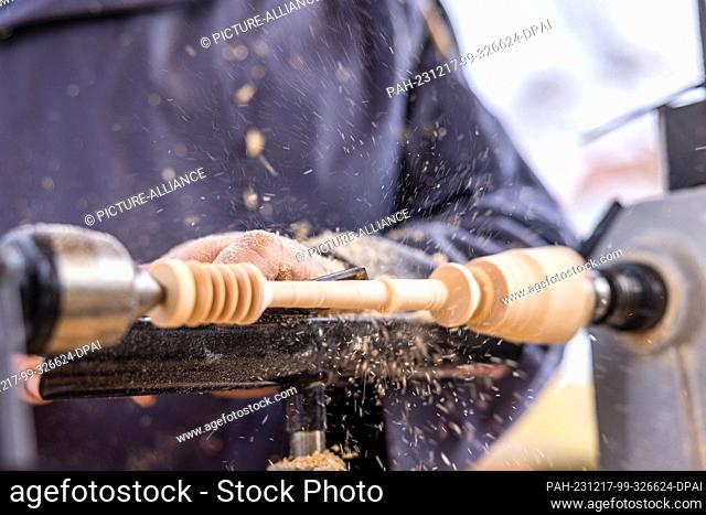 16 December 2023, Brandenburg, Leuthen: A craftsman makes a honey spoon on a lathe at a small Advent market. Advent and Christmas markets are also held in many...