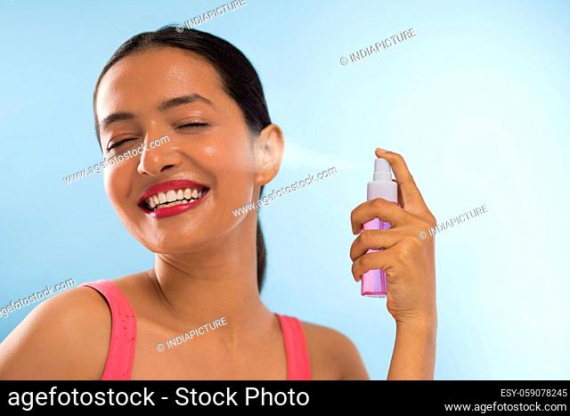 Close Up portrait with Rose Water spraying on Face of young beautiful woman