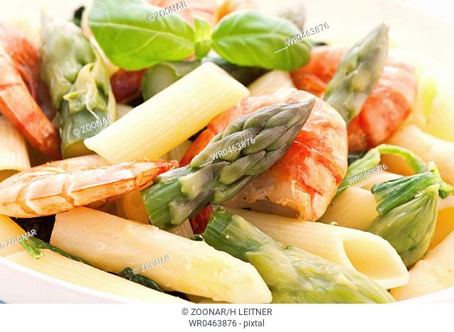 Rigatoni with shrimp and asparagus as closeup on a white plate