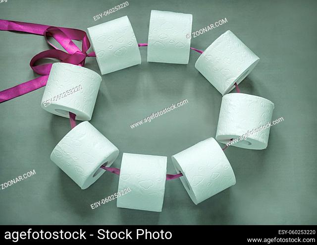 Rolls of white toilet paper are connected with a ribbon in a bundle. Top view, close-up. Copy space