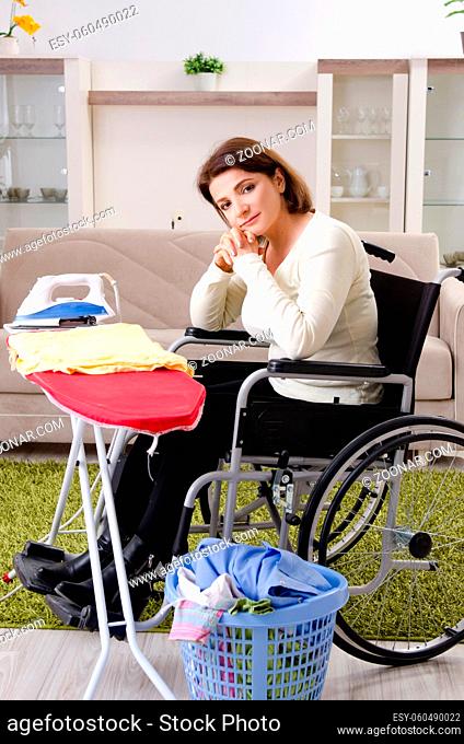 Woman in wheelchair ironing at home