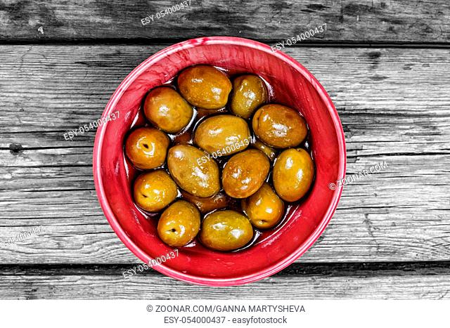 Fresh green olives in pink bowl on wooden table background. rustic style. Top view with copy space