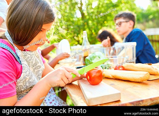 Kinder bereiten Salat zu im Kochkurs im Ferienlager und lernen über gesunde Ernährung