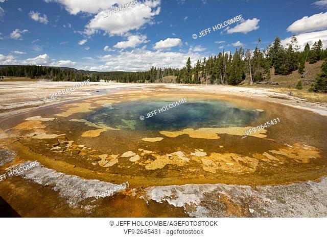Colorful orange and blue water at Chromatic Pool hot springs under a sunny blue sky in the Upper Geyser Basin of Yellowstone National Park, Wyoming